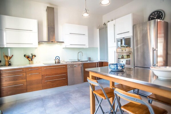 Una cocina moderna con armarios de madera, electrodomésticos de acero inoxidable y una isla central con taburetes de bar.