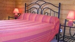 A bed with a striped blanket, two bedside lamps, and a wooden headboard. - Comfortable waterside chalet with private pond fishing in the Morvan. (Moux-En-Morvan)