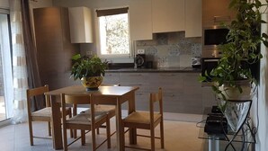 A modern kitchen with wooden cabinets, a dining table with chairs, and a potted plant. - Charming residence in the heart of green Provence (Bras)
