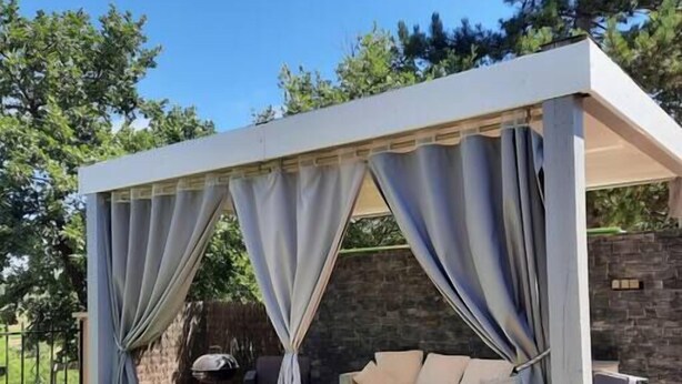 A covered outdoor seating area with a sofa and a table, surrounded by a stone wall and greenery. - Charming residence in the heart of green Provence (Bras)