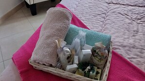 A neatly made bed with a pink blanket, a white chair, and a basket of toiletries on the bed. - Charming residence in the heart of green Provence (Bras)