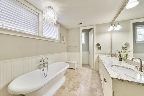 A spacious bathroom with a freestanding bathtub, a large vanity with a sink, and a mirror. - Sunset Rentals | Corine Lane 13 (Hilton Head Island)