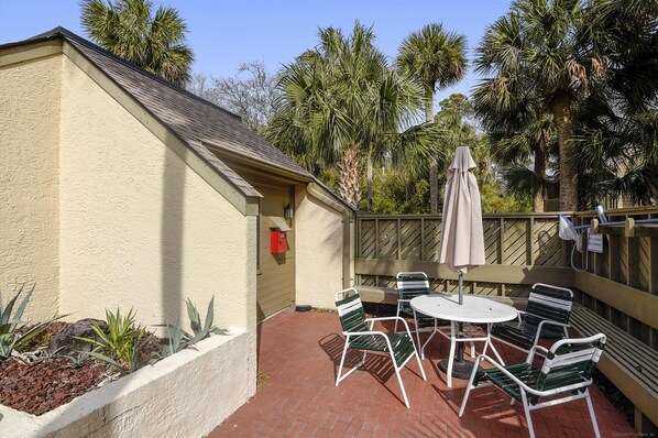 A patio with a table and chairs, a red mailbox, and a wooden fence. - Sunset Rentals | Colonnade Club 206 (Hilton Head Island)