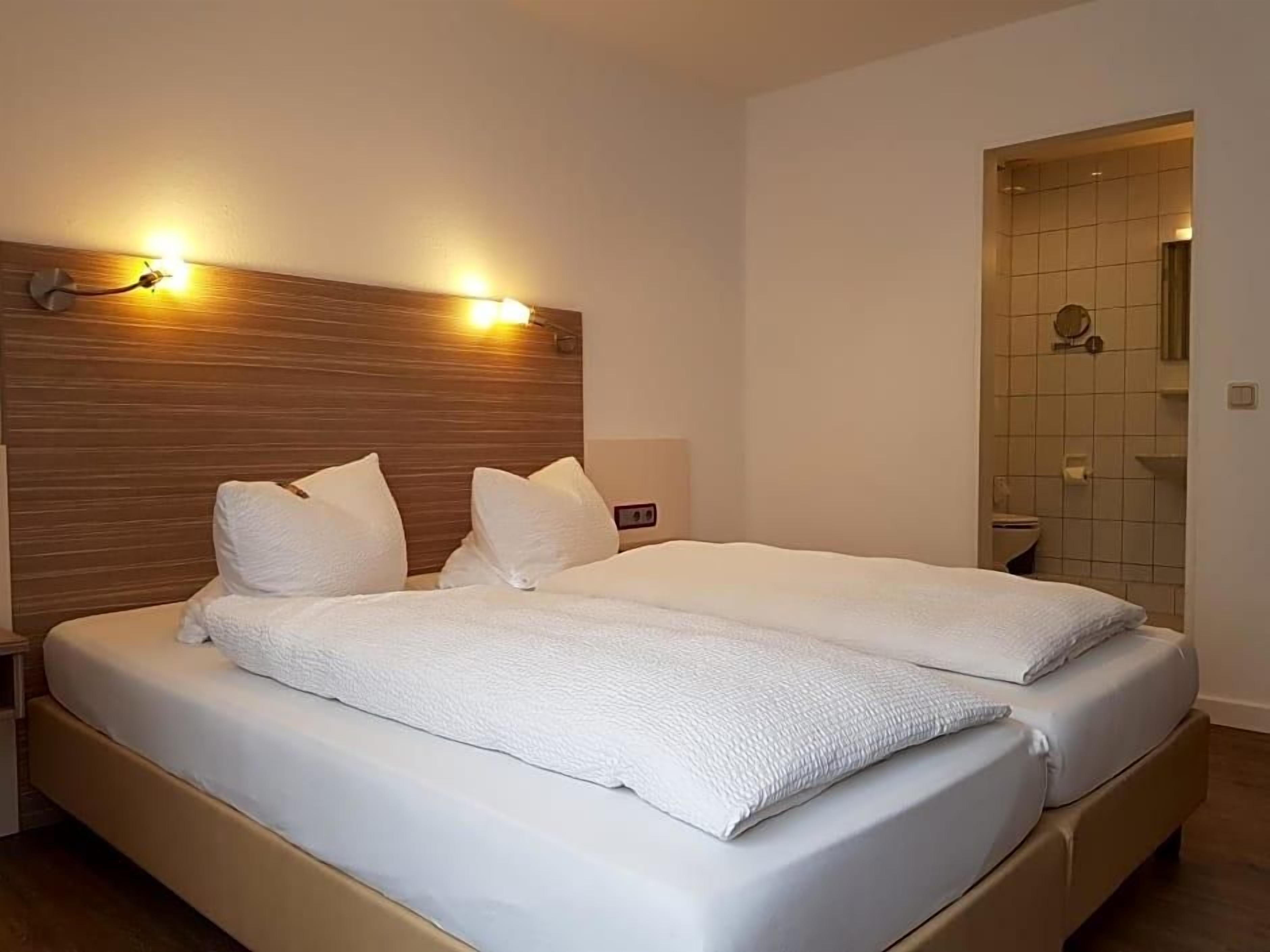 A double bed with a wooden headboard, two bedside tables, and a small bedside lamp.