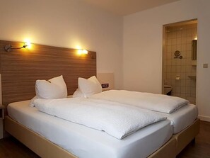 A double bed with a wooden headboard, two bedside tables, and a small bedside lamp.