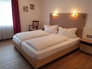A double bed with a wooden headboard, two bedside tables, and a chair.
