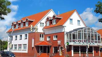 A building with a red-tiled roof, a glass storefront, and a sign that reads 'Gaststätte Zum M.'