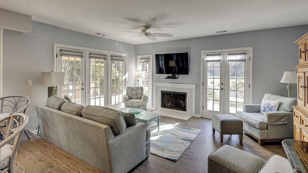 A spacious living room with a fireplace, comfortable seating, and a ceiling fan. - Sunset Rentals | Evian 156 (Hilton Head Island)