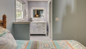 A narrow hallway leading to a bathroom with a vanity and a mirror. - Sunset Rentals | Evian 156 (Hilton Head Island)