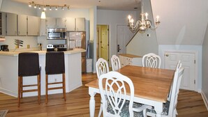 Une cuisine moderne dotée d’appareils électroménagers en acier inoxydable, d’une table à manger en bois et de chaises blanches.