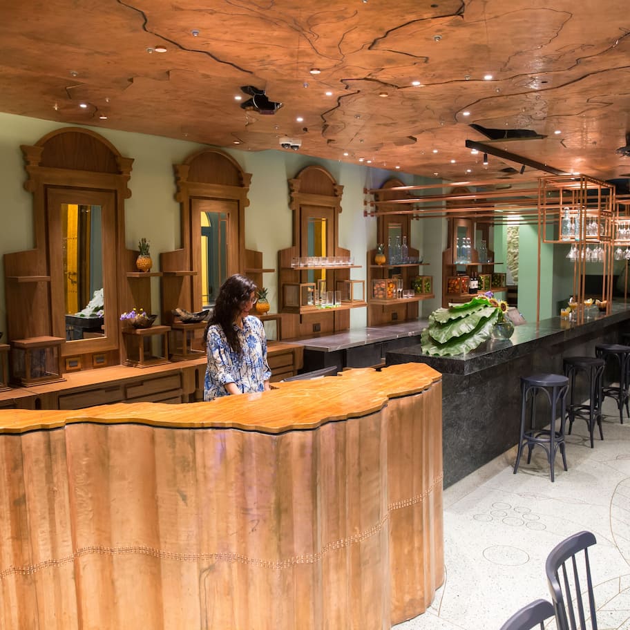 A restaurant with a wooden reception desk, bar area, and seating.