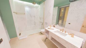 A modern bathroom with a glass-enclosed shower, a white marble sink, and a large mirror.