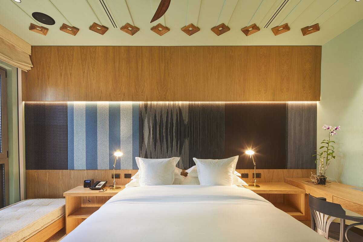 Ein modernes Hotelzimmer mit einem großen Bett, Nachttischen, einem Schreibtisch und einem Sessel.