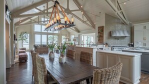 A spacious kitchen with a large island, wooden dining table, and wicker chairs. - Sunset Rentals | Duck Hawk 27 (Hilton Head Island)