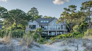 A two-story house with a large balcony, surrounded by dense vegetation and sand dunes. - Sunset Rentals | Duck Hawk 27 (Hilton Head Island)