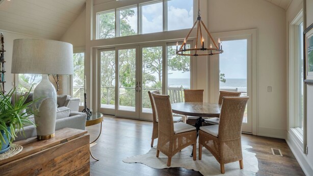 A spacious dining area with a high ceiling, large windows, and a view of the ocean. - Sunset Rentals | Duck Hawk 27 (Hilton Head Island)