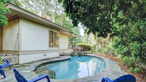 A swimming pool with blue chairs, a house, and surrounding greenery. - Sunset Rentals | Mooring Buoy 175 (Hilton Head Island)