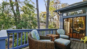 A deck with wicker furniture and a glass door leading to an outdoor area. - Sunset Rentals | Gloucester 79 (Hilton Head Island)