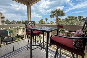 Un espace extérieur abrité, avec une table et des chaises, d’où l’on peut admirer des palmiers et un bâtiment en arrière-plan.