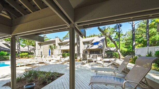 Ein überdachter Außenbereich mit Pool, Liegestühlen und einer Holzterrasse.