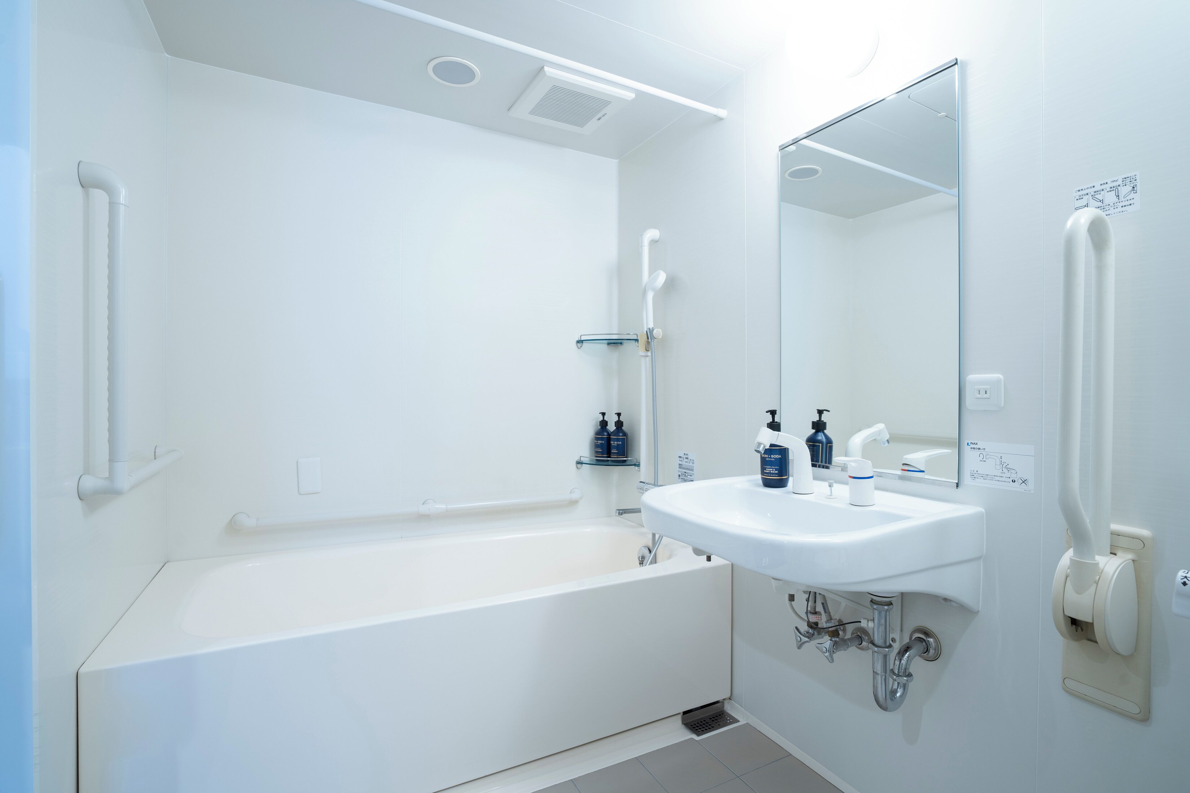 A modern bathroom with a white bathtub, a sink, and a mirror.