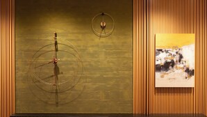 A modern interior with a wooden panel wall, a black bench, and a framed abstract painting.