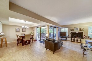 Relax in this stylish living room with a large sofa, dining area, and fireplace, opening to a balcony with a view.