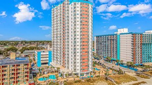 A high-rise hotel with multiple floors, a swimming pool, and a beach area. - Palace 1404 (Myrtle Beach)