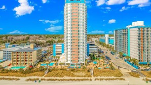 A tall hotel with multiple floors, a swimming pool, and a beach view. - Palace 1404 (Myrtle Beach)