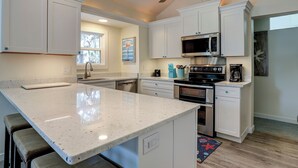 Una cocina con armarios blancos, microondas, horno y ventilador de techo.