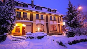 Um hotel com fachada tradicional, entrada visível e paisagem coberta de neve.
