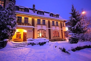 A hotel with a traditional facade, a visible entrance, and snow-covered surroundings. - Hotel Karkonosze (Kamienna Gora)