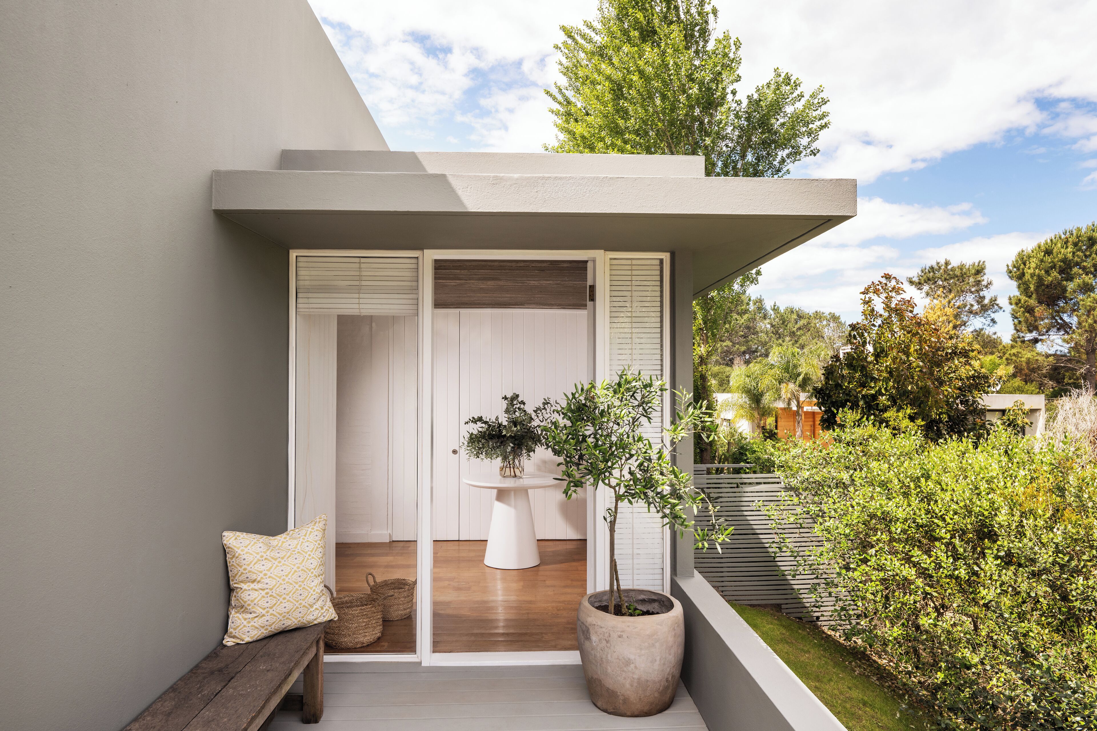 A modern balcony with a bench, a potted plant, and a small table.