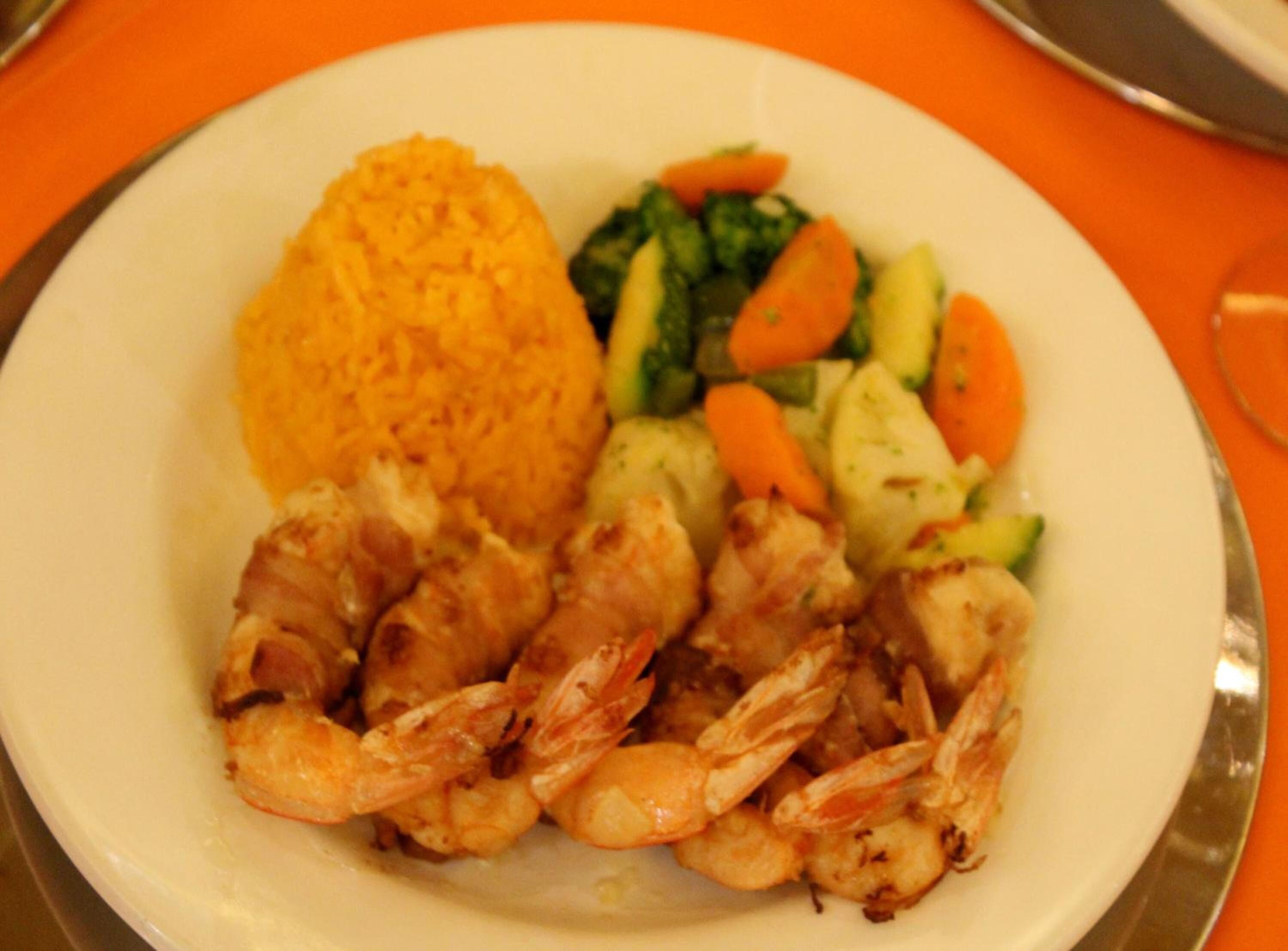 Prato com camarões grelhados, arroz e legumes variados.