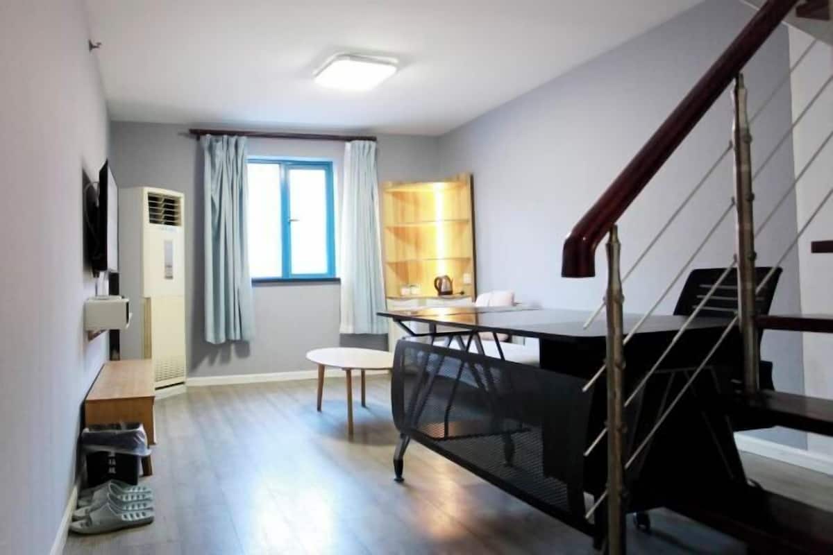 A compact living space with a dining area, a staircase, and a kitchenette.