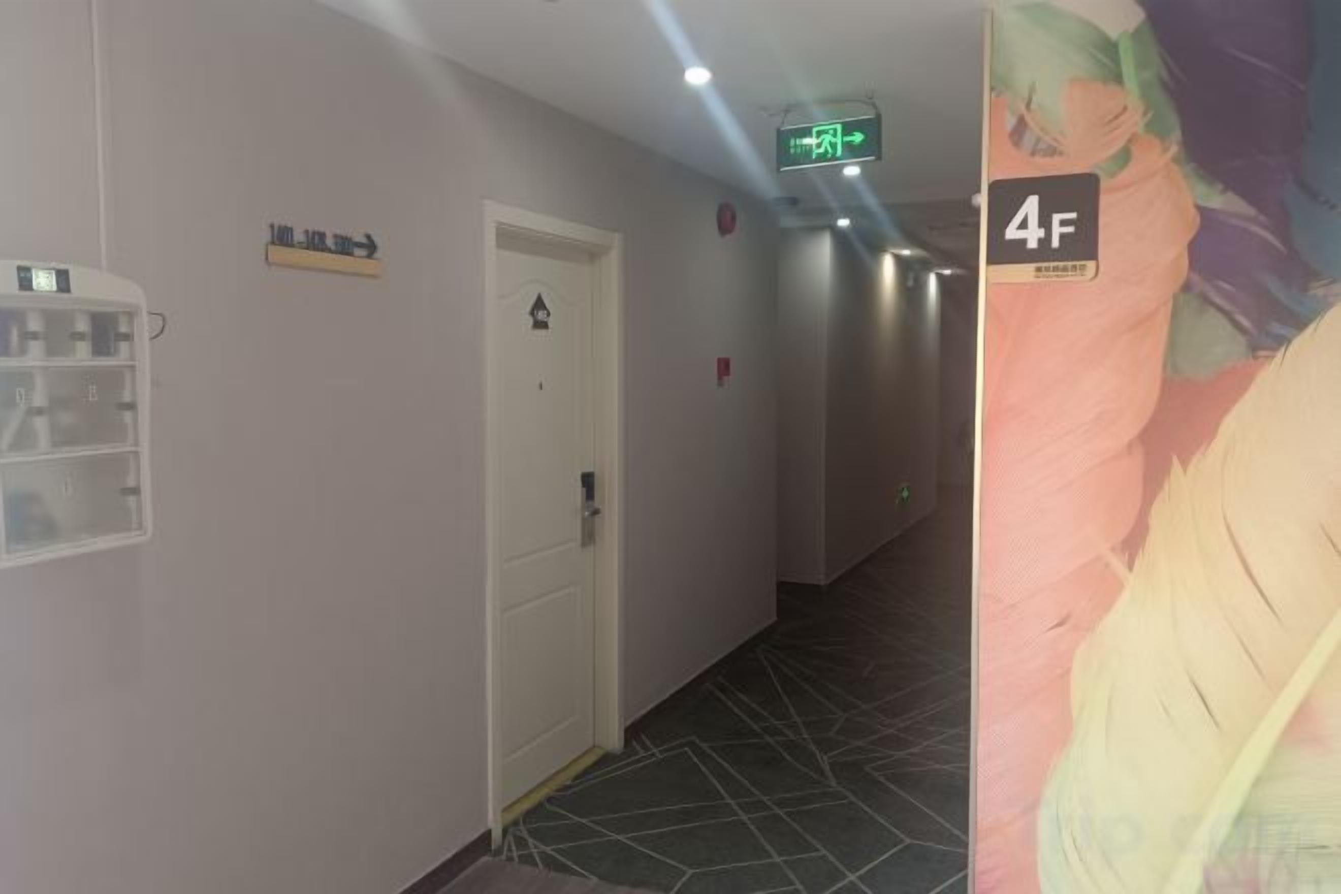Un pasillo con una puerta, un interruptor de luz y una lámpara fijada a la pared.