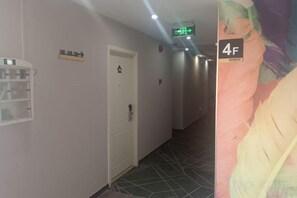 A hallway with a door, a light switch, and a wall-mounted light fixture. - OK Boutique Hotel (Shanghai)