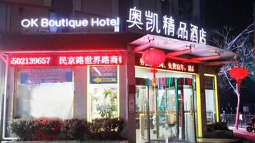 A hotel with a neon sign, a storefront with glass windows, and a red lantern outside.
