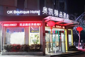 A hotel with a neon sign, a storefront with glass windows, and a red lantern outside. - OK Boutique Hotel (Shanghai)