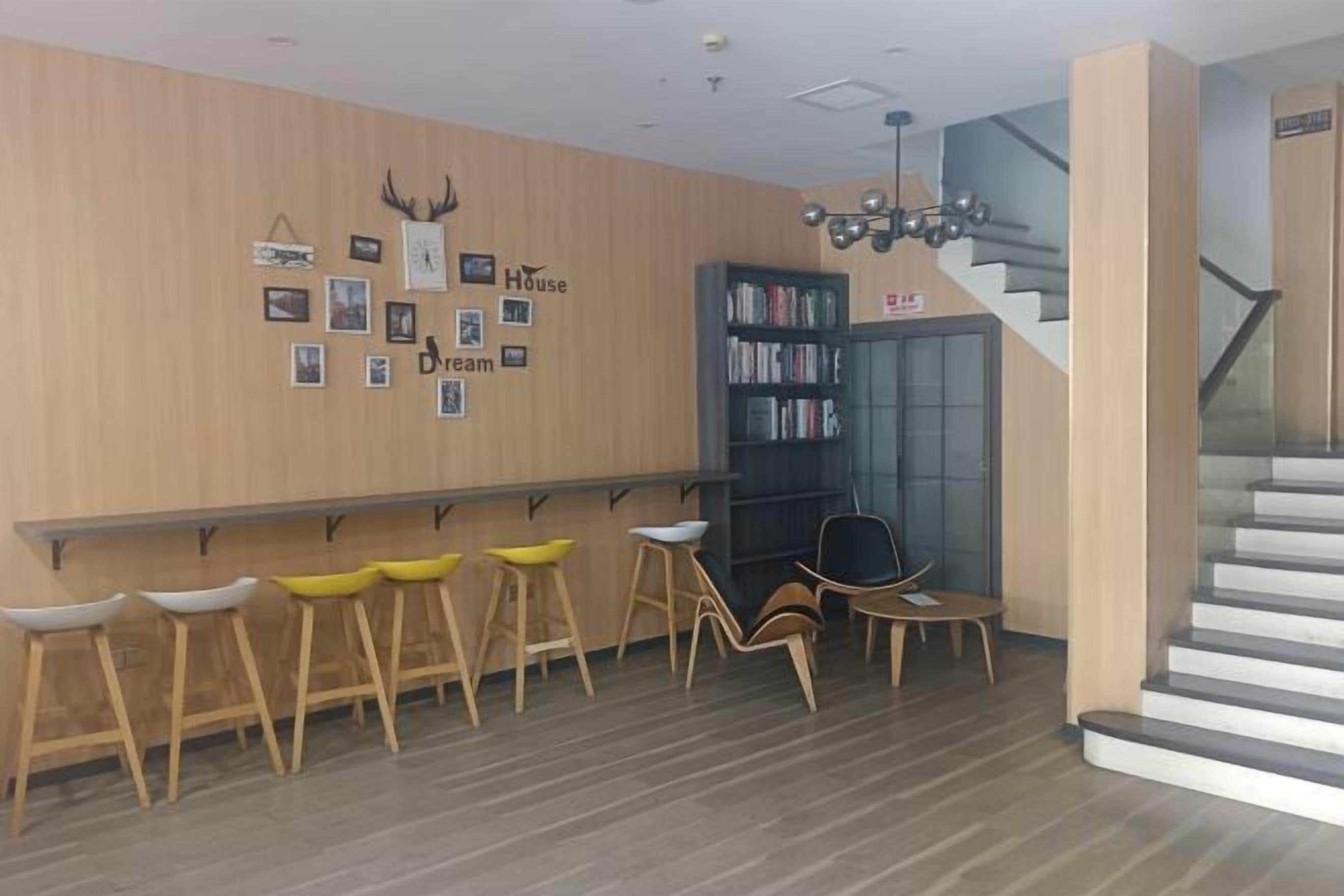 A hotel lobby with a wooden wall, a reception desk, a staircase, and a bookshelf.
