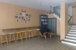 A hotel lobby with a wooden wall, a reception desk, a staircase, and a bookshelf. - OK Boutique Hotel (Shanghai)