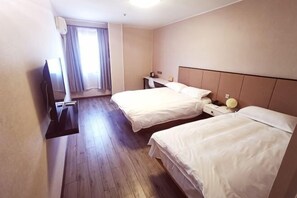 Habitación de hotel con dos camas, televisión, escritorio y ventana con cortinas.