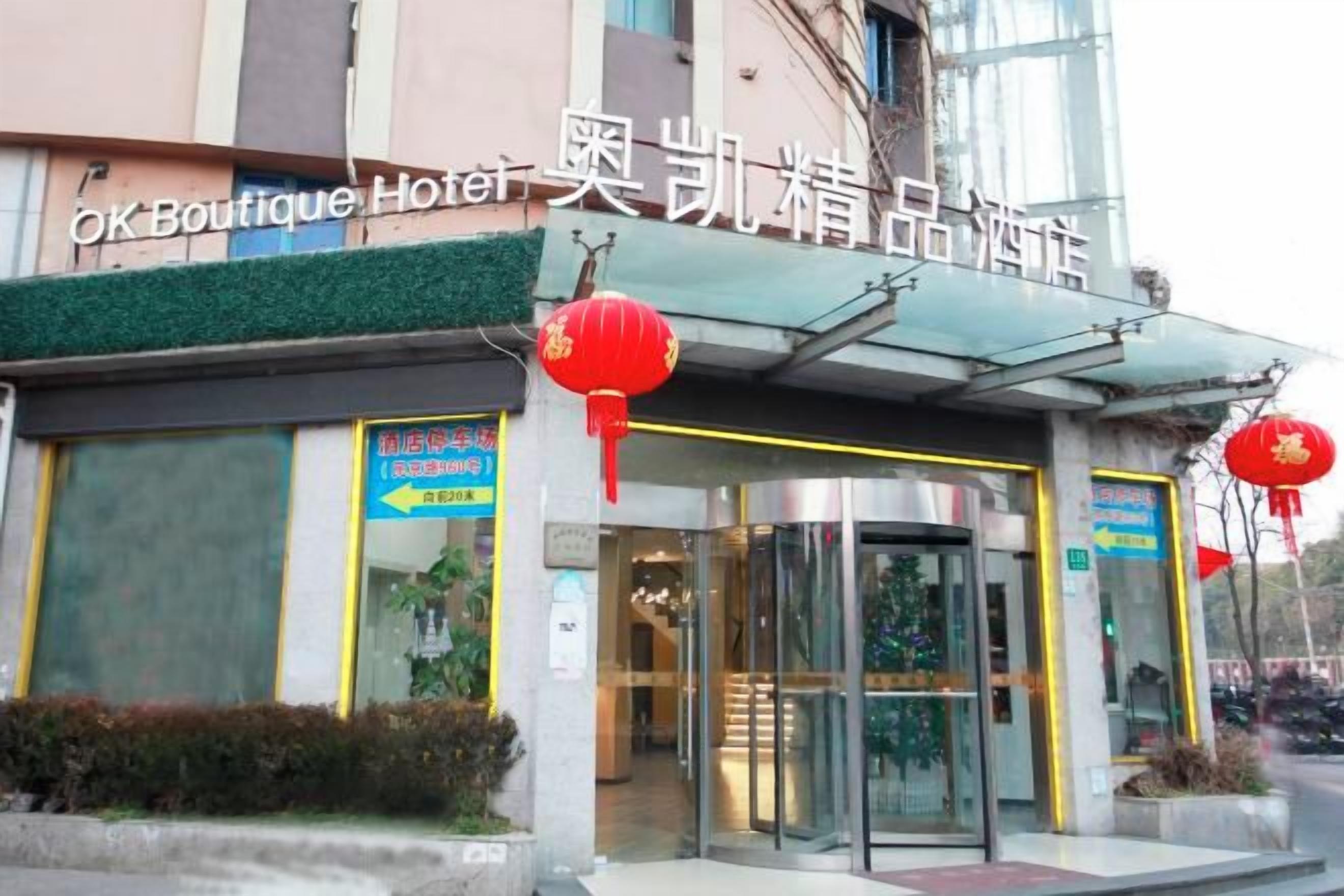 A hotel entrance with a glass door, signage, and red lanterns.