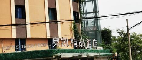 A hotel with a modern facade, a visible entrance, and a signboard with text.