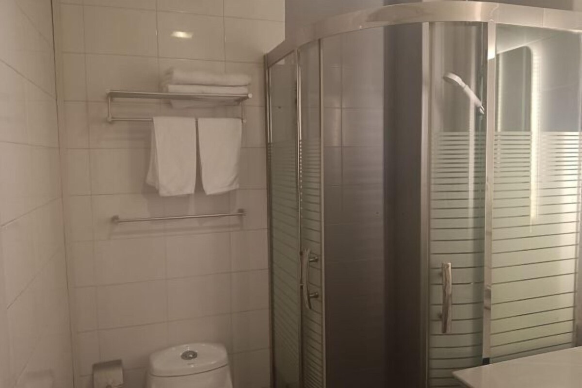 A modern bathroom with a glass-enclosed shower, a toilet, and a towel rack.
