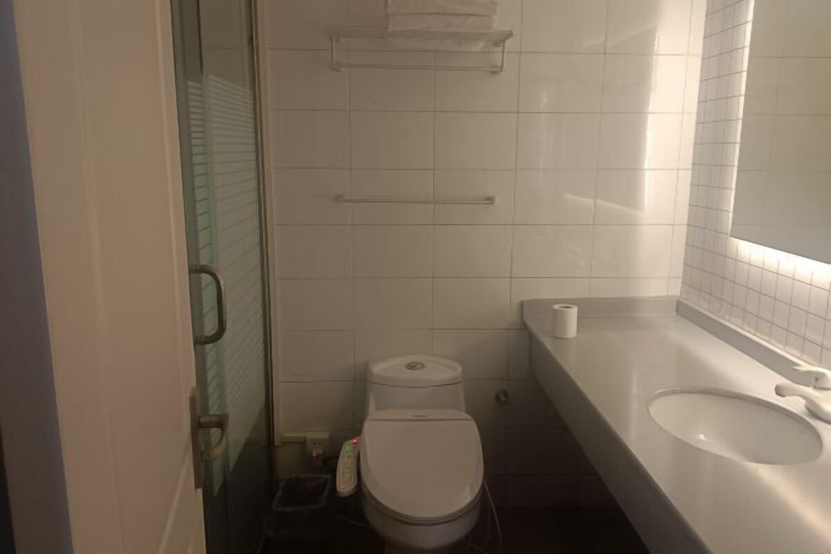 A small bathroom with a toilet, a sink, and a mirror. There is a towel rack above the toilet and a shelf above the sink.