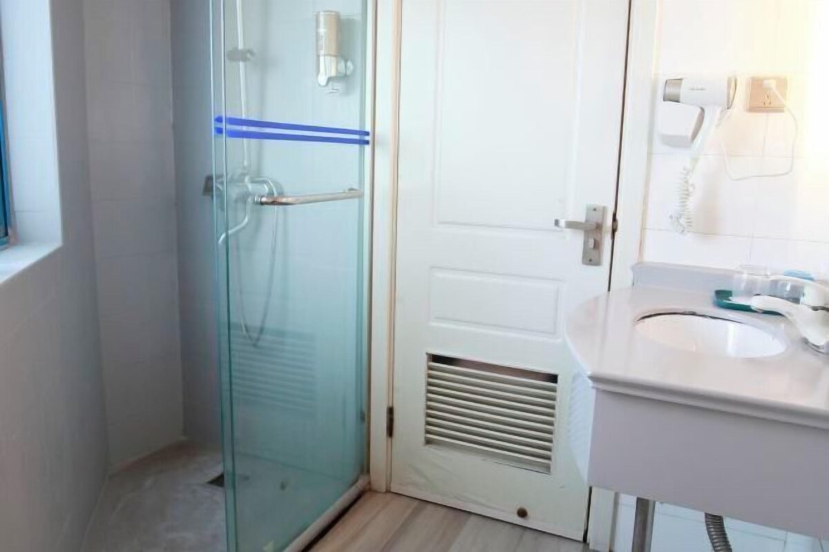 A bathroom with a glass shower enclosure, a white sink, and a mirror.