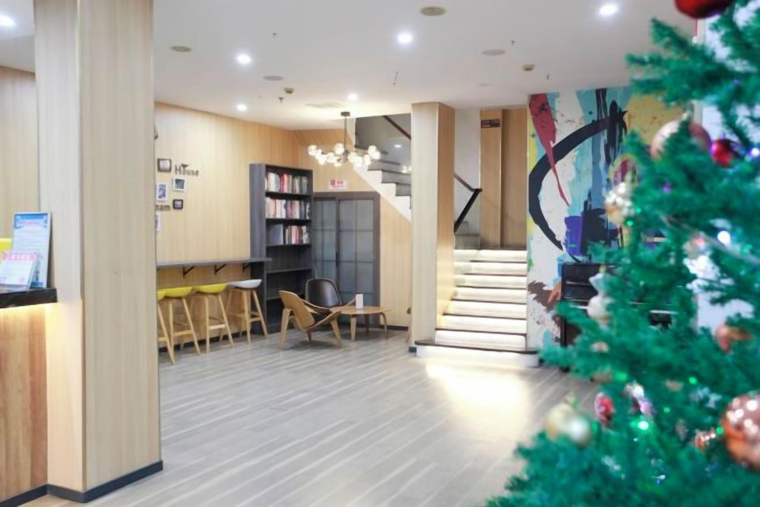 A modern interior with a staircase, a reception desk, and a Christmas tree.