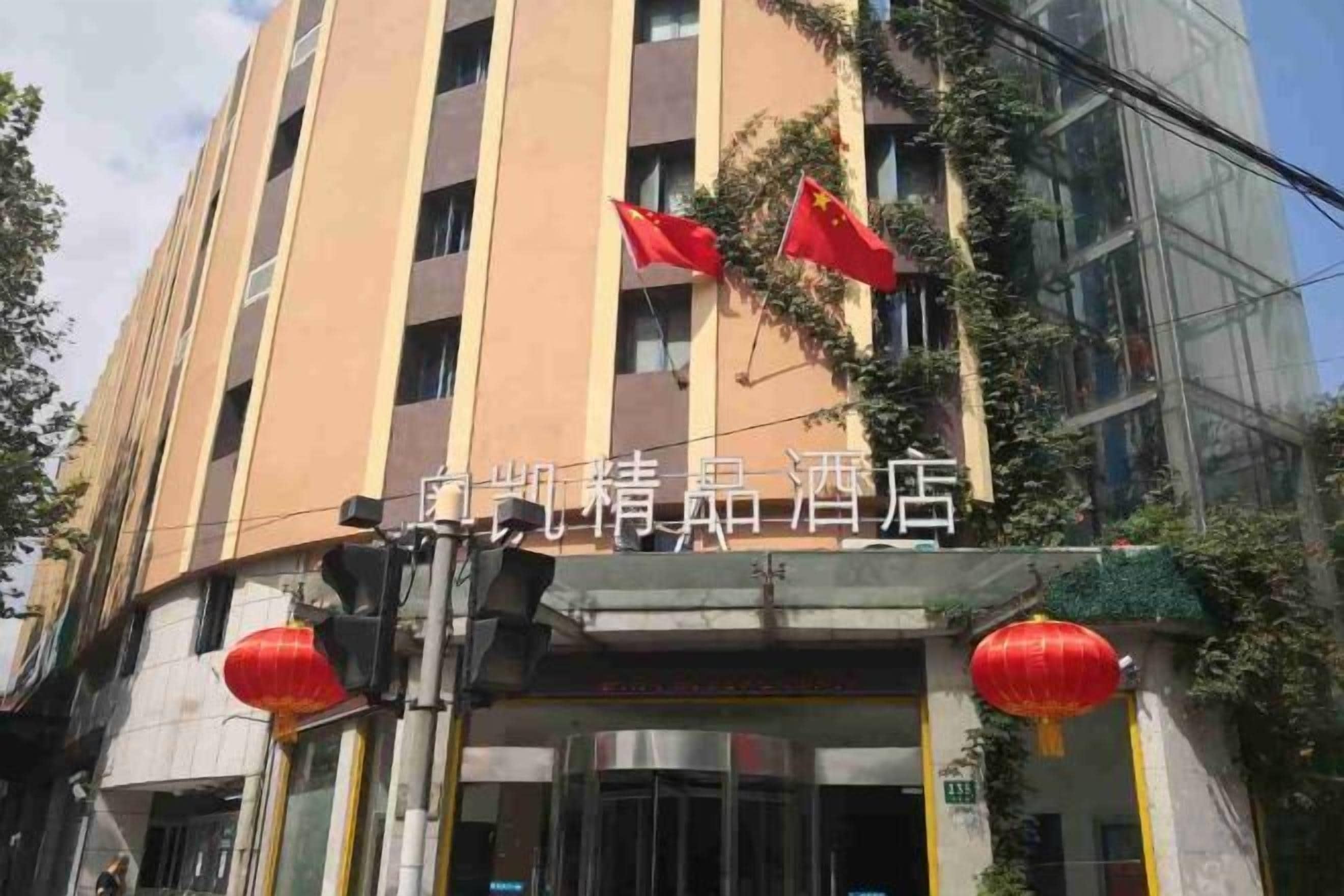 A hotel with a modern facade, red flags, and traditional red lanterns.