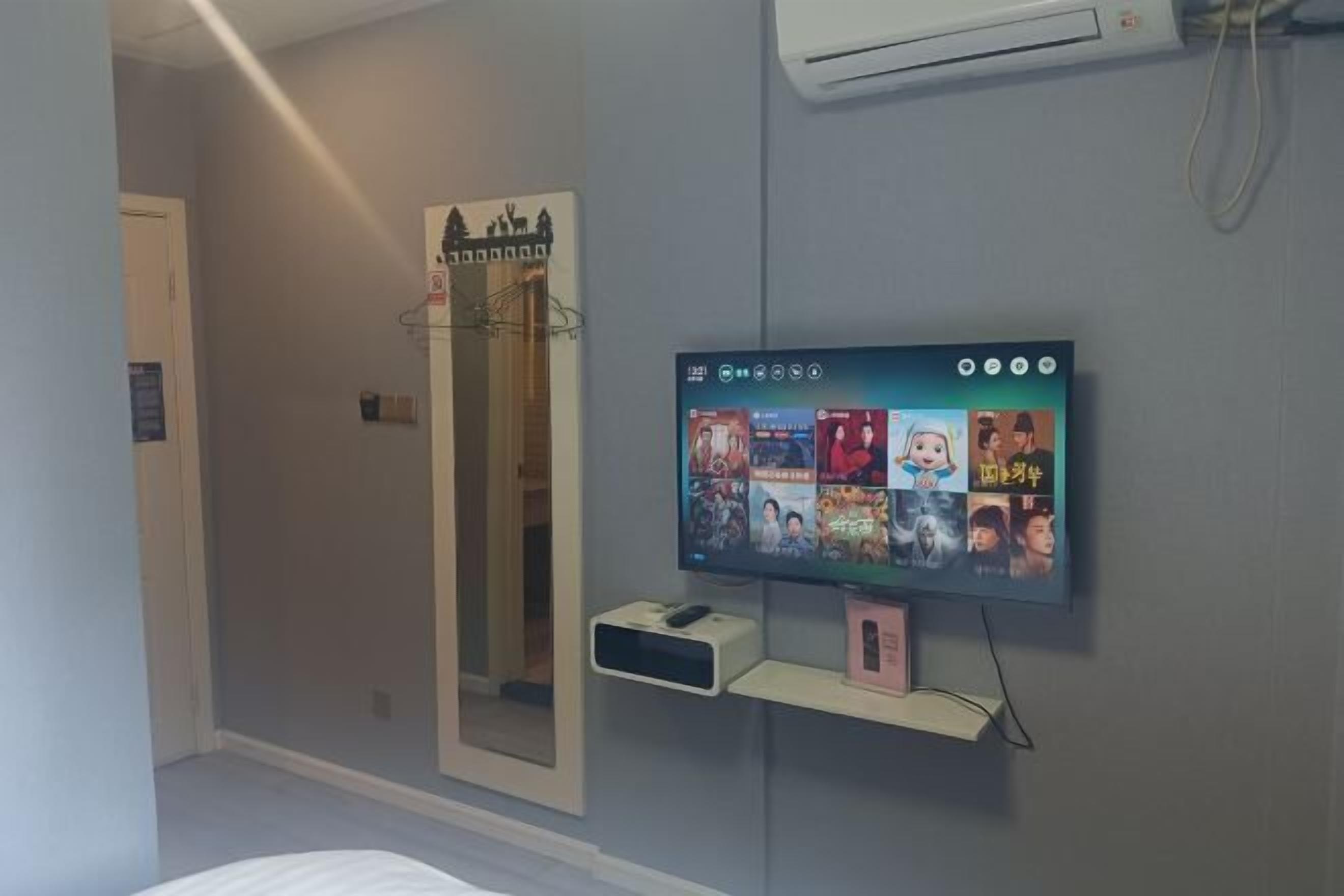 Una camera da letto con una TV a parete, un comodino e uno specchio.